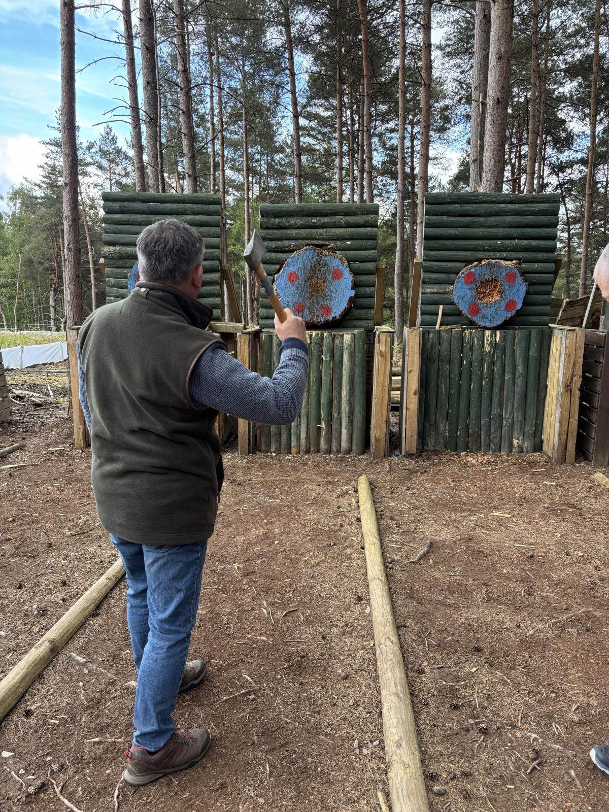 Thrower mid-swing with an axe raised in front of the timber targets