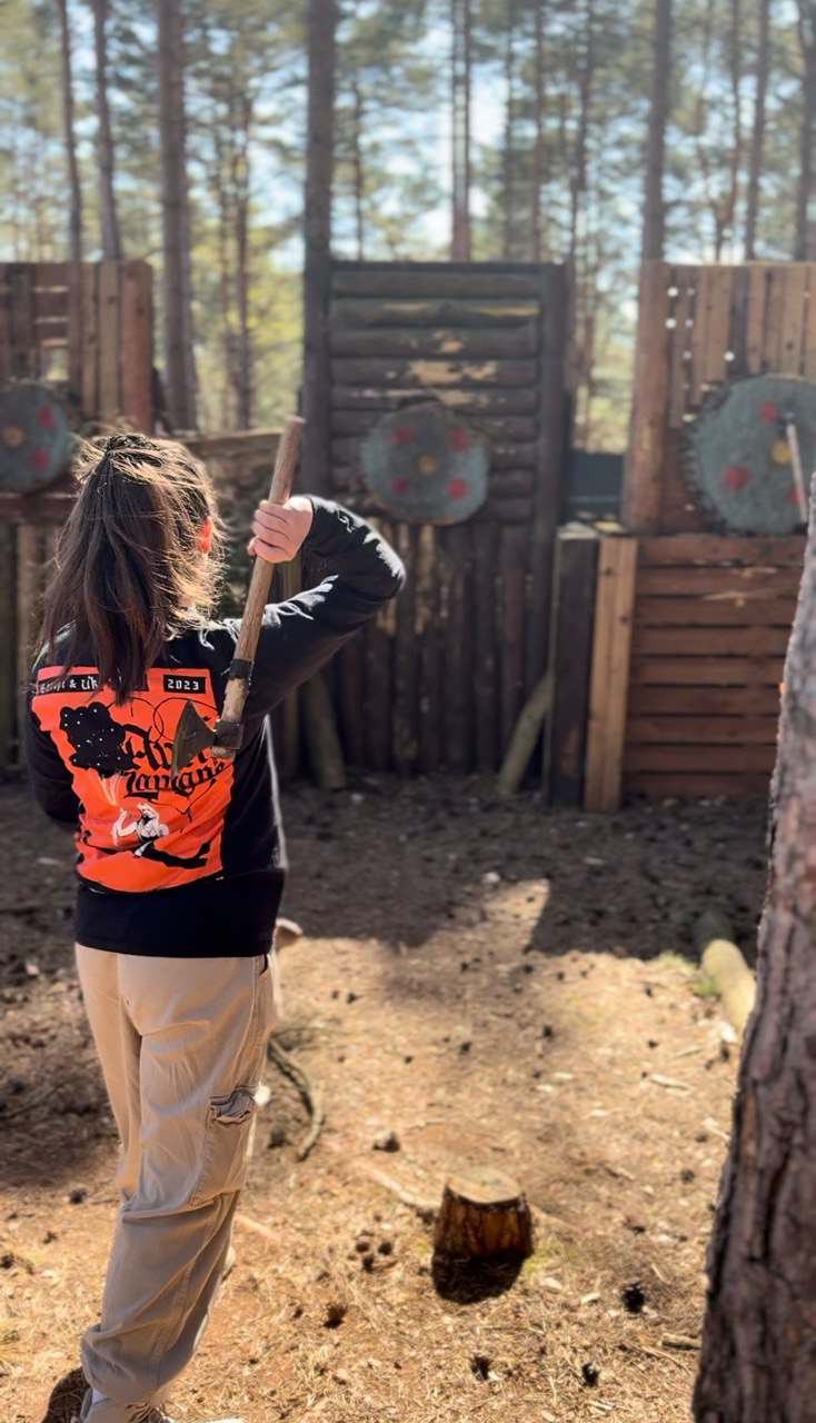 Teen participant throwing an axe at a woodland target