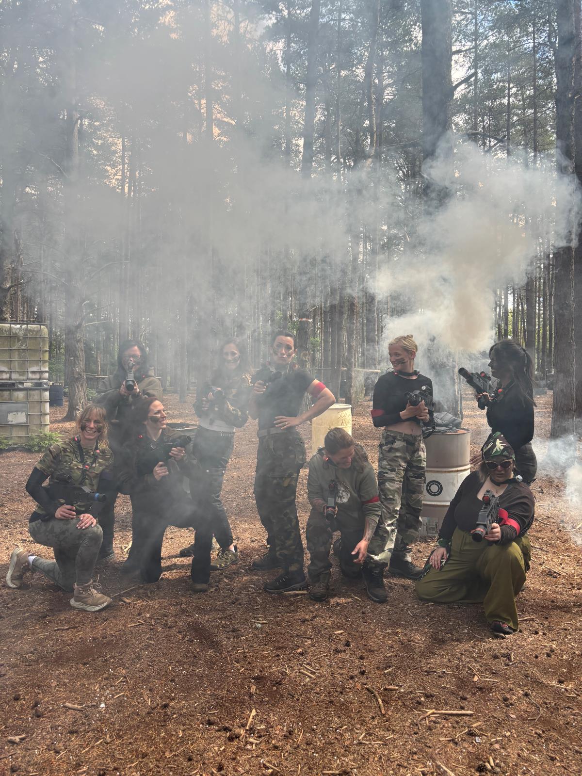 Adult group in camouflage surrounded by smoke during a laser tag game