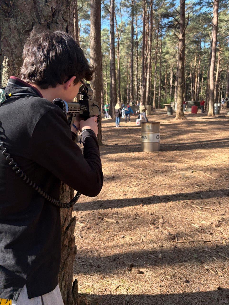 Young player in camouflage taking aim with a laser rifle